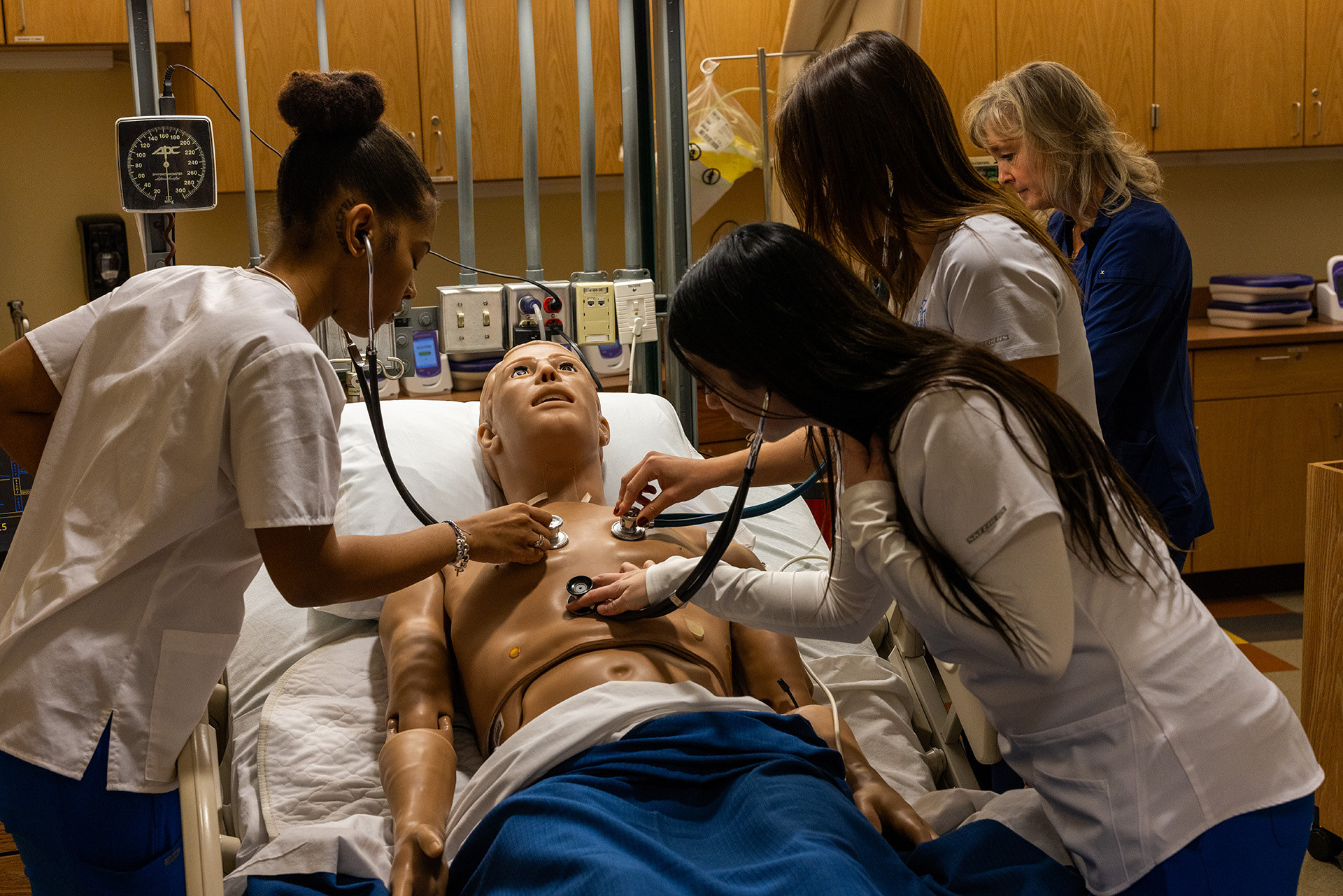 Students listening to heart in nursing class