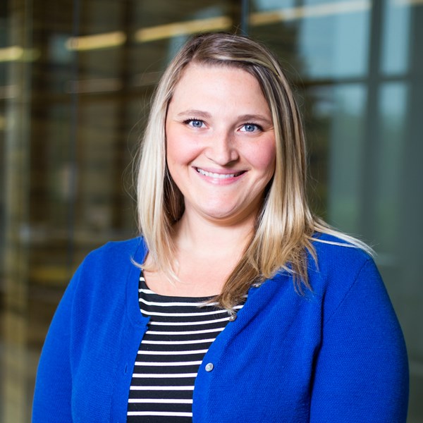Smiling female with blonde hair, blue cardigan and black and white striped shirt