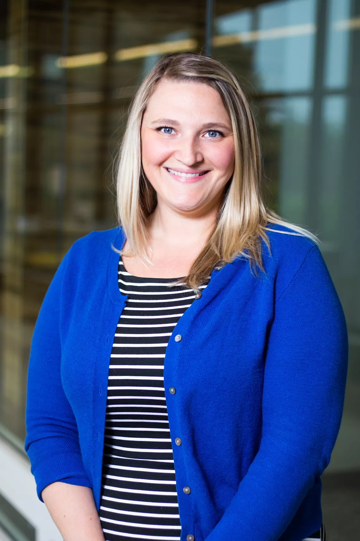 Smiling female with blonde hair, blue cardigan and black and white striped shirt
