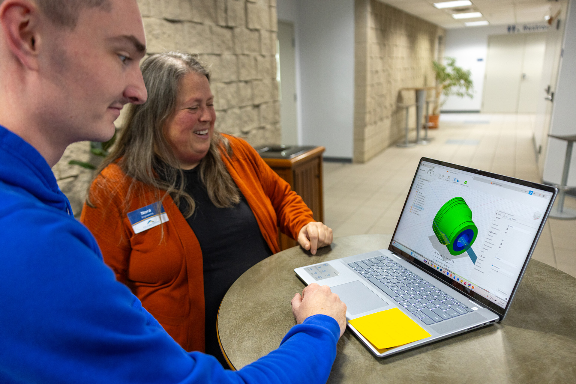 Instructor and student looking at CAD modeling on laptop.