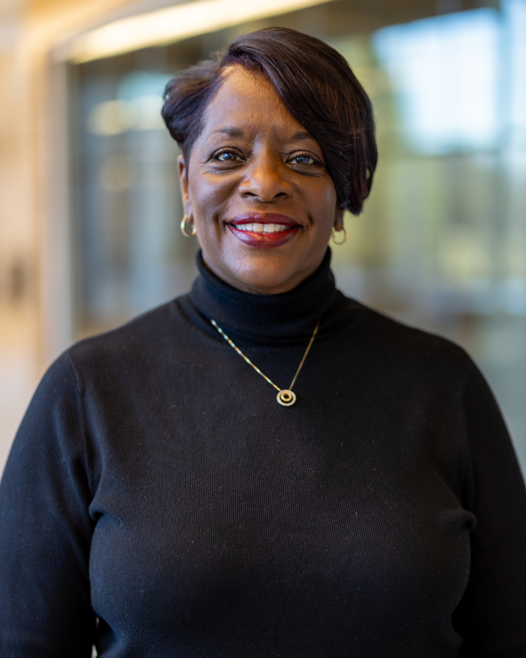 Sharon Evans, a women with short brown hair smiling, wearing a black turtleneck shirt.