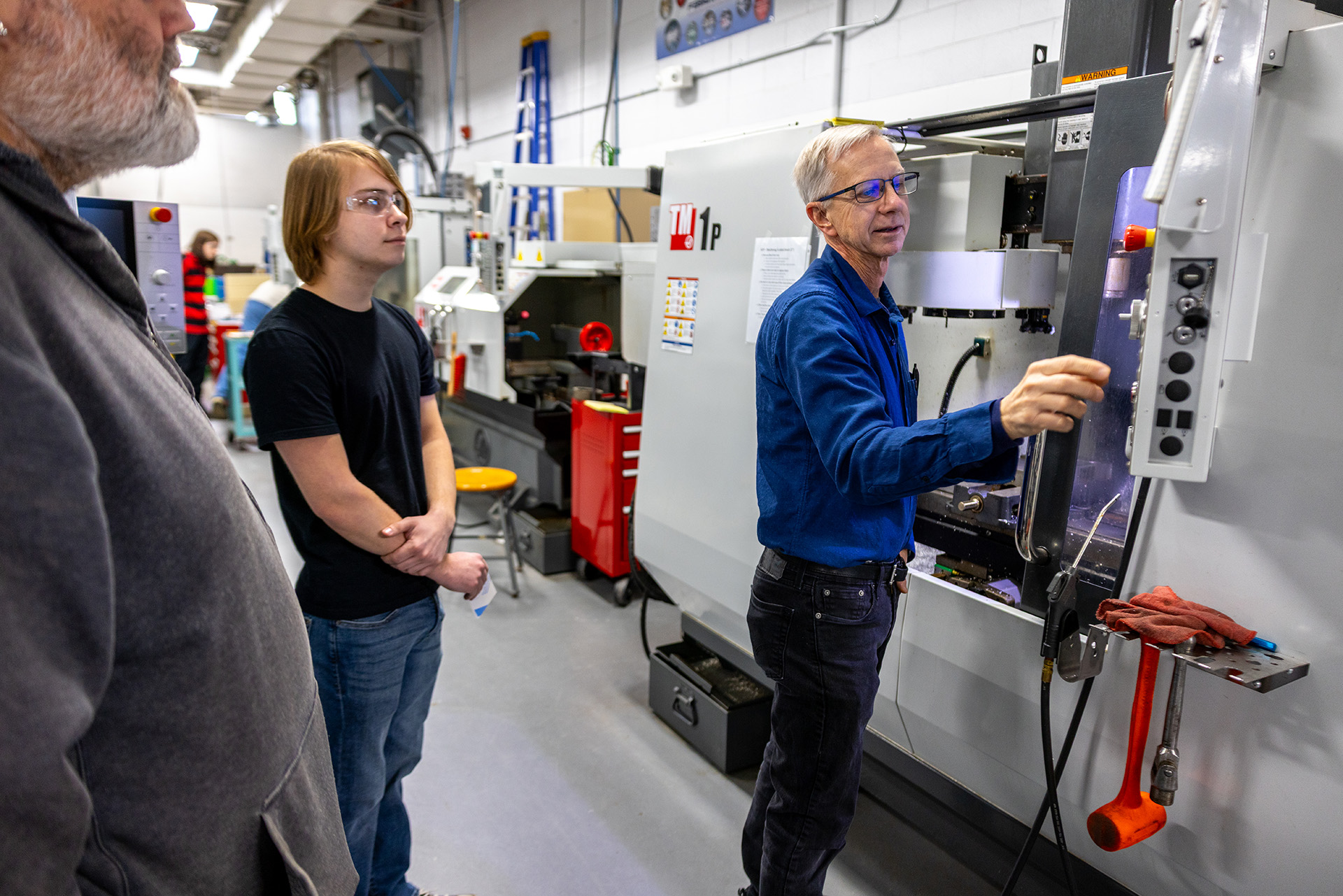 Two men standing at CNC machine control panel.