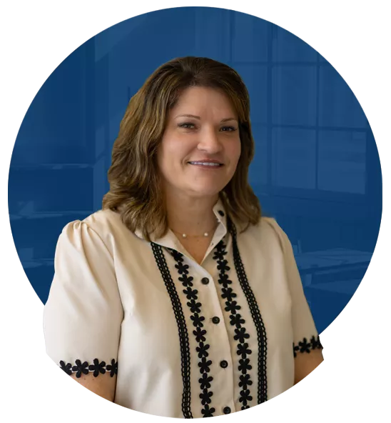 Laura Whetstone, a person with blonde hair wearing a yellow floral blouse and black blazer smiling.