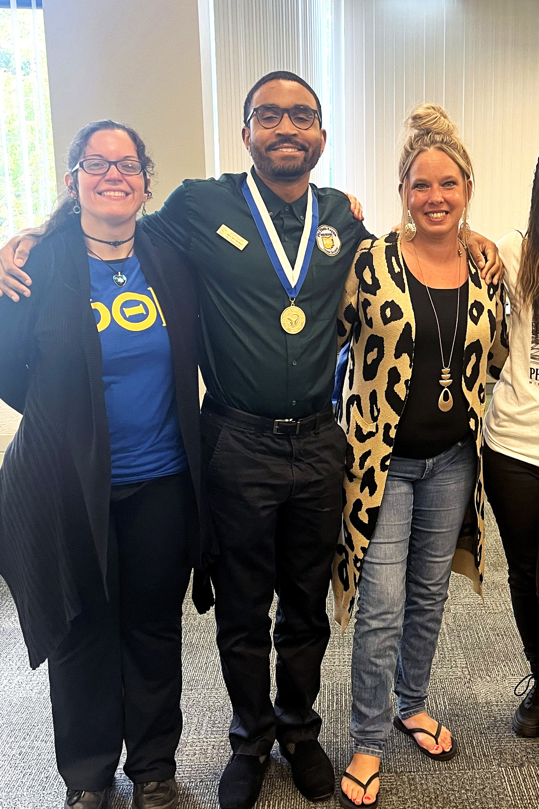 Three students in PTK honors program smile with a metal award.