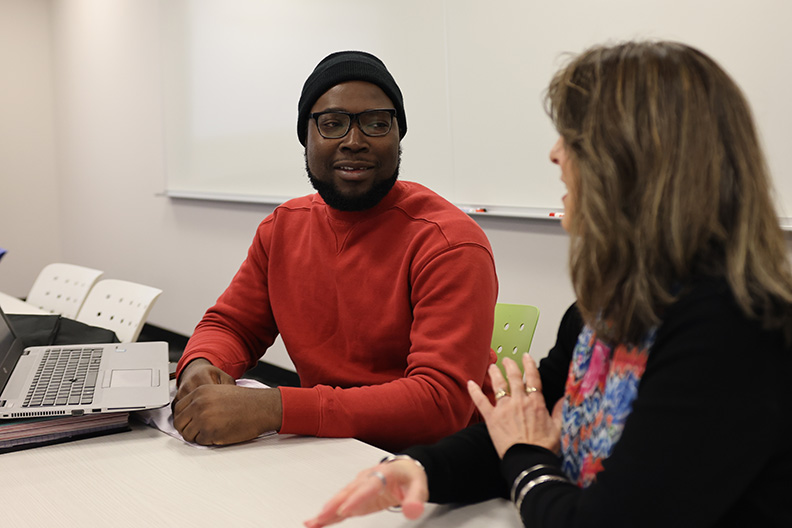 Student and teach sit at table going over course material