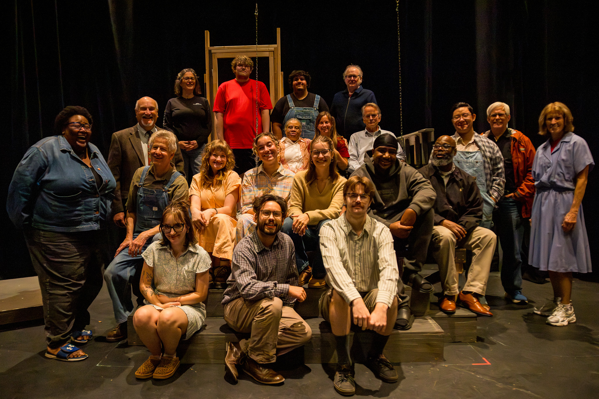 Multiple people sitting and standing on a stage posing for a photo