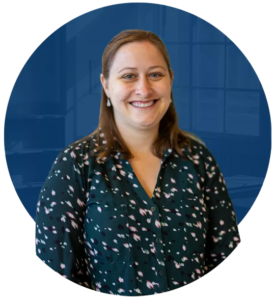 Laura McCabe, a person with brown, straight hair wearing a patterned teal blouse, smiling.