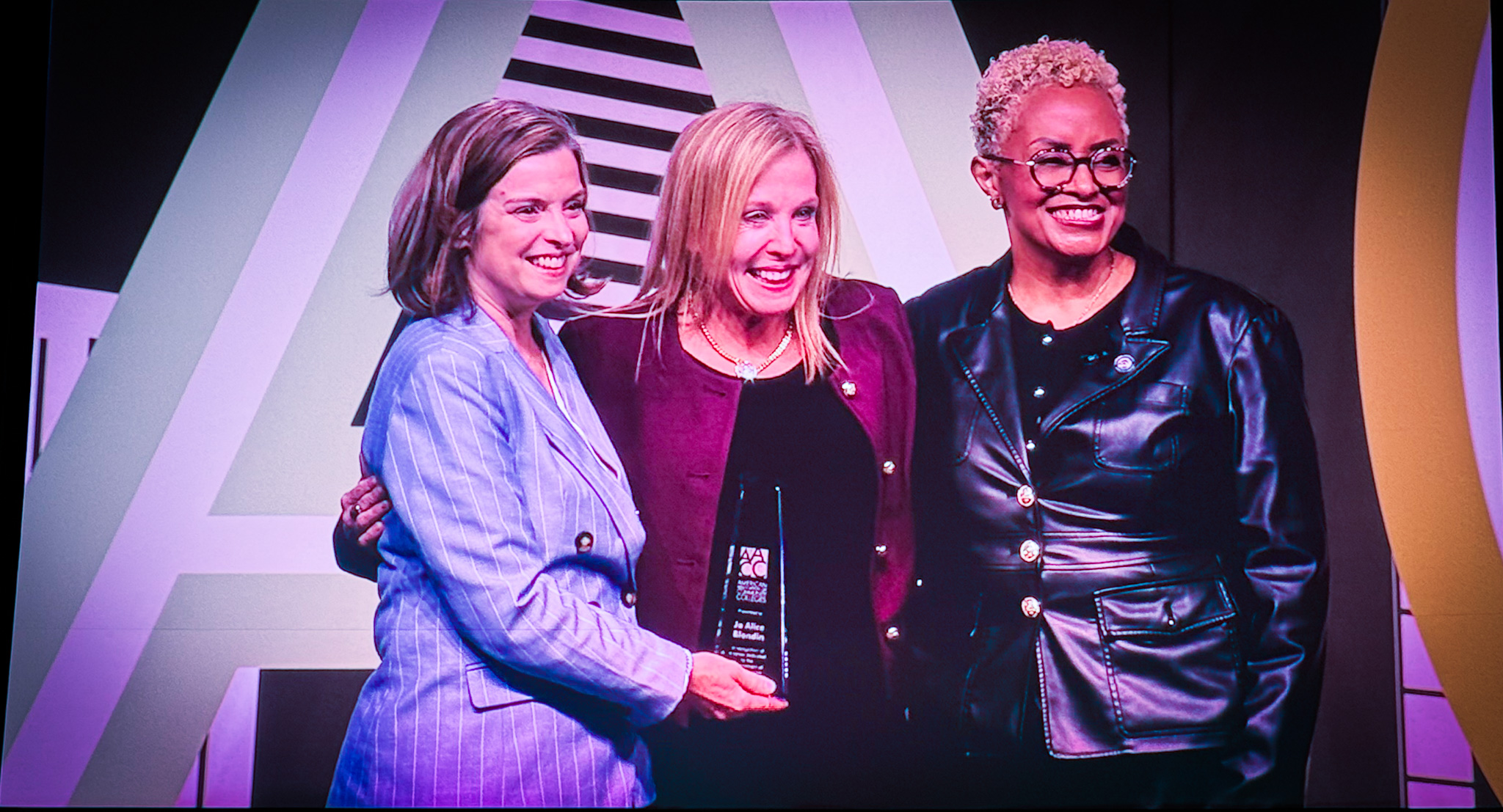 Three women at awards ceremony holding an award