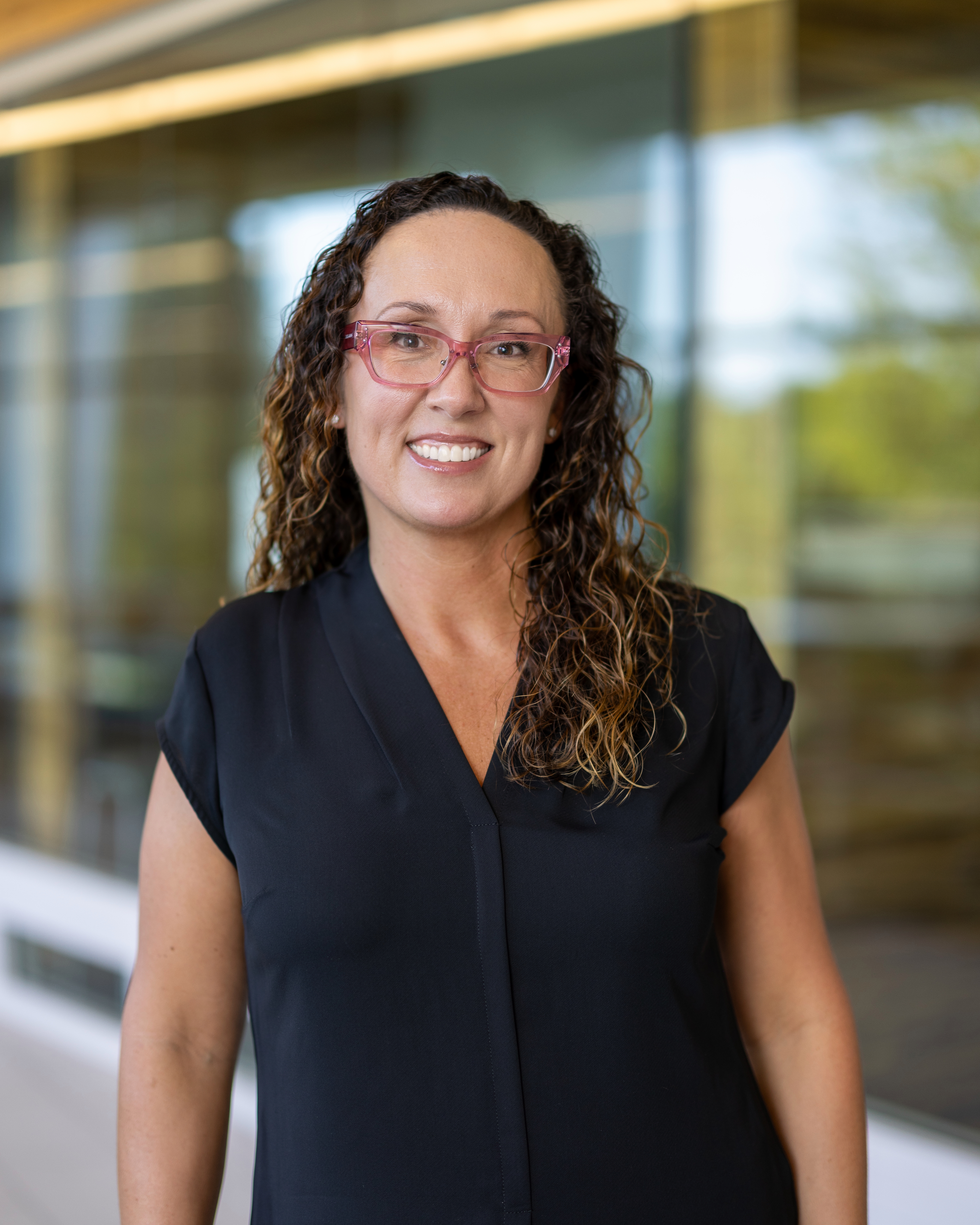 Woman with dark hair and glasses with navy blue shirt