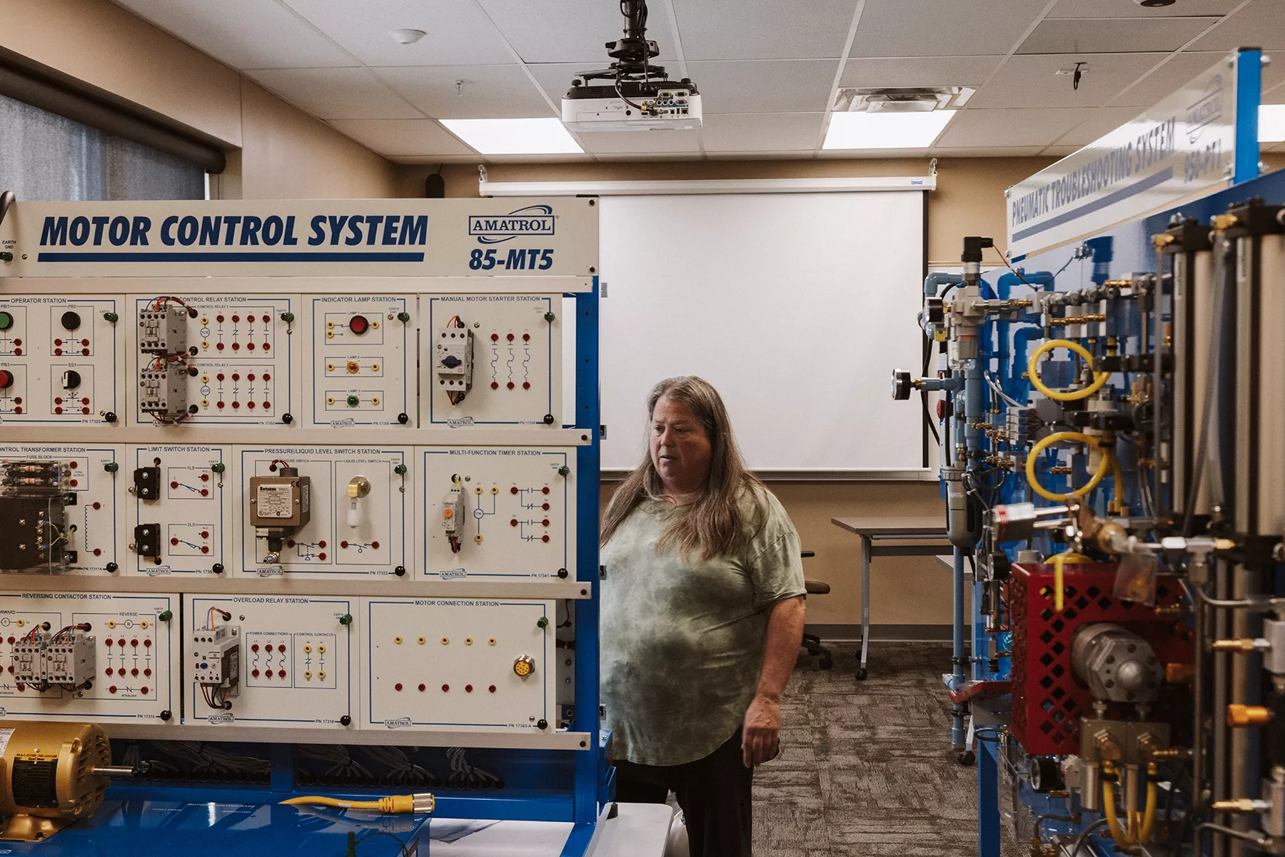 Training board and equipment with knobs, connectors, lights with instructor observing the machine.