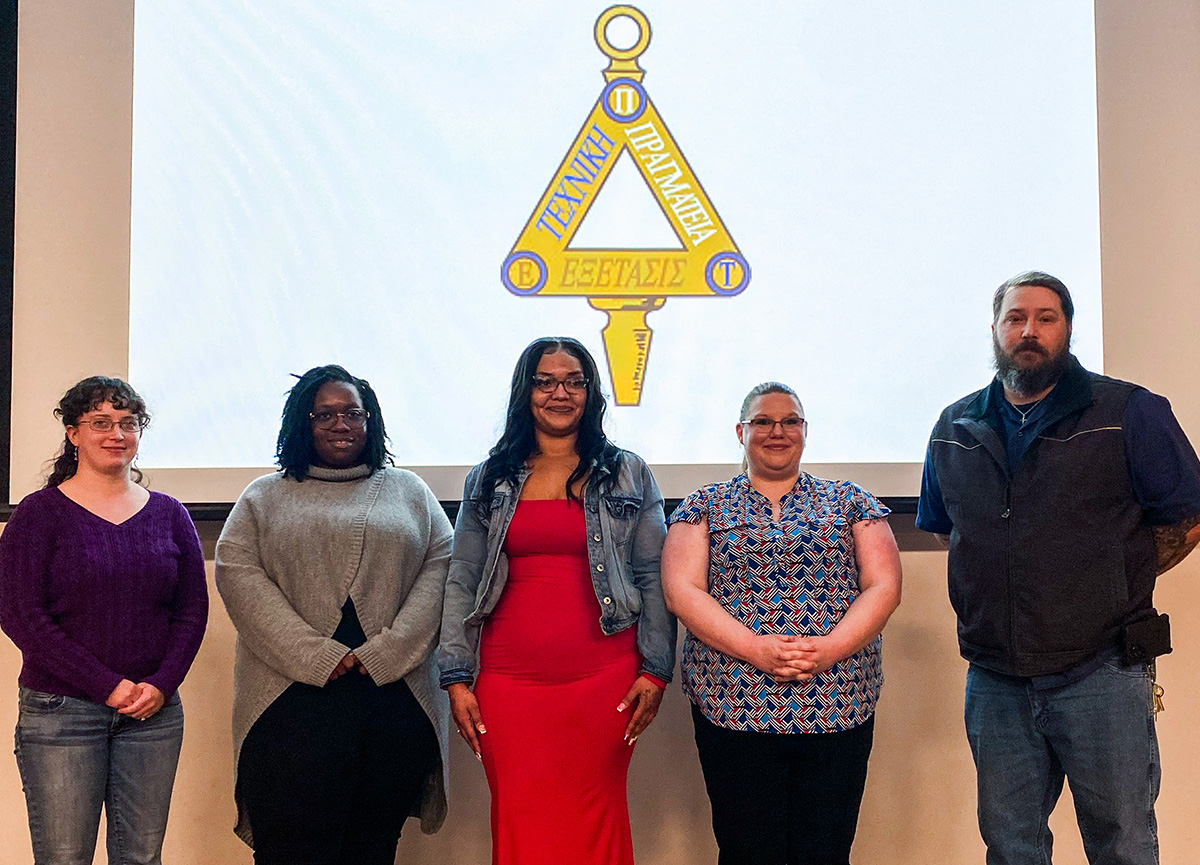 Five EPT student inductees in front of EPT logo.