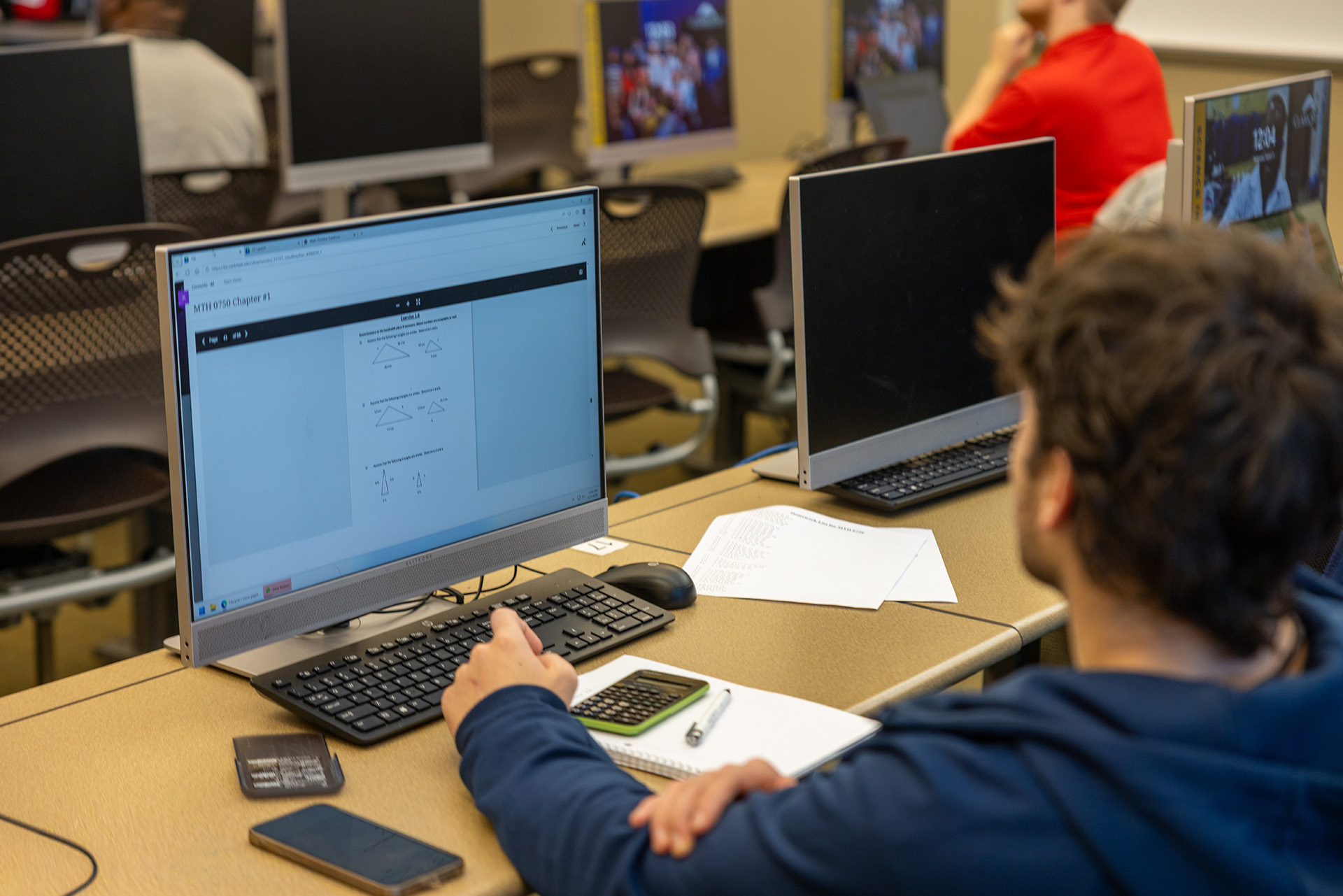 Student sitting at computer working through math worksheet on geometry.