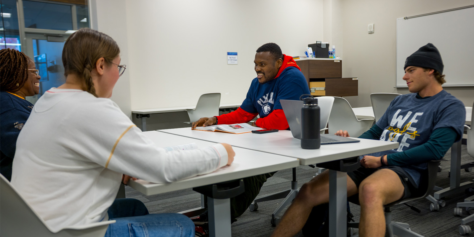 Students sitting at at able with laptops and textbooks