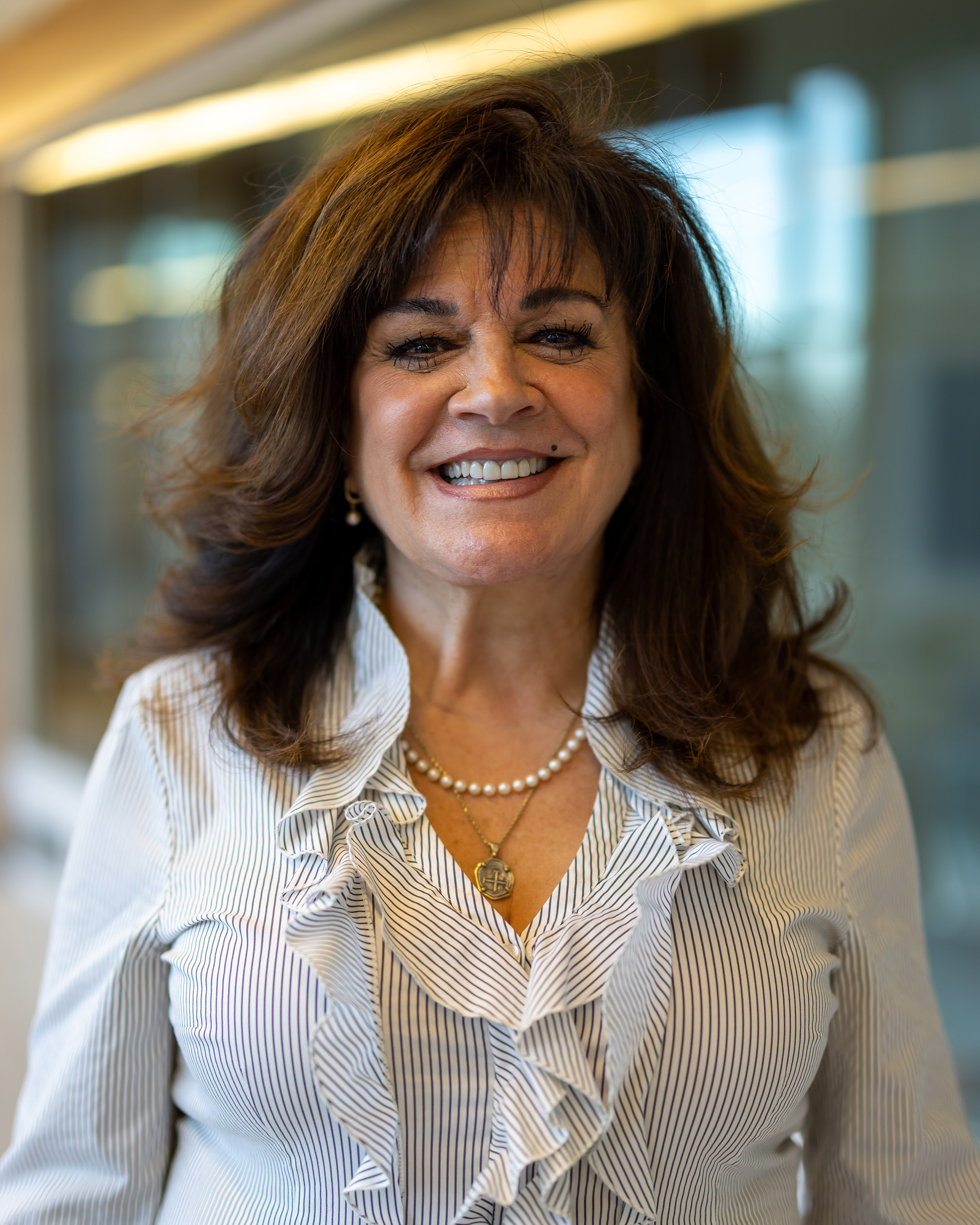 Becka Rowland Buckley a women with brown hair smiling, wearing a black and white striped blouse.