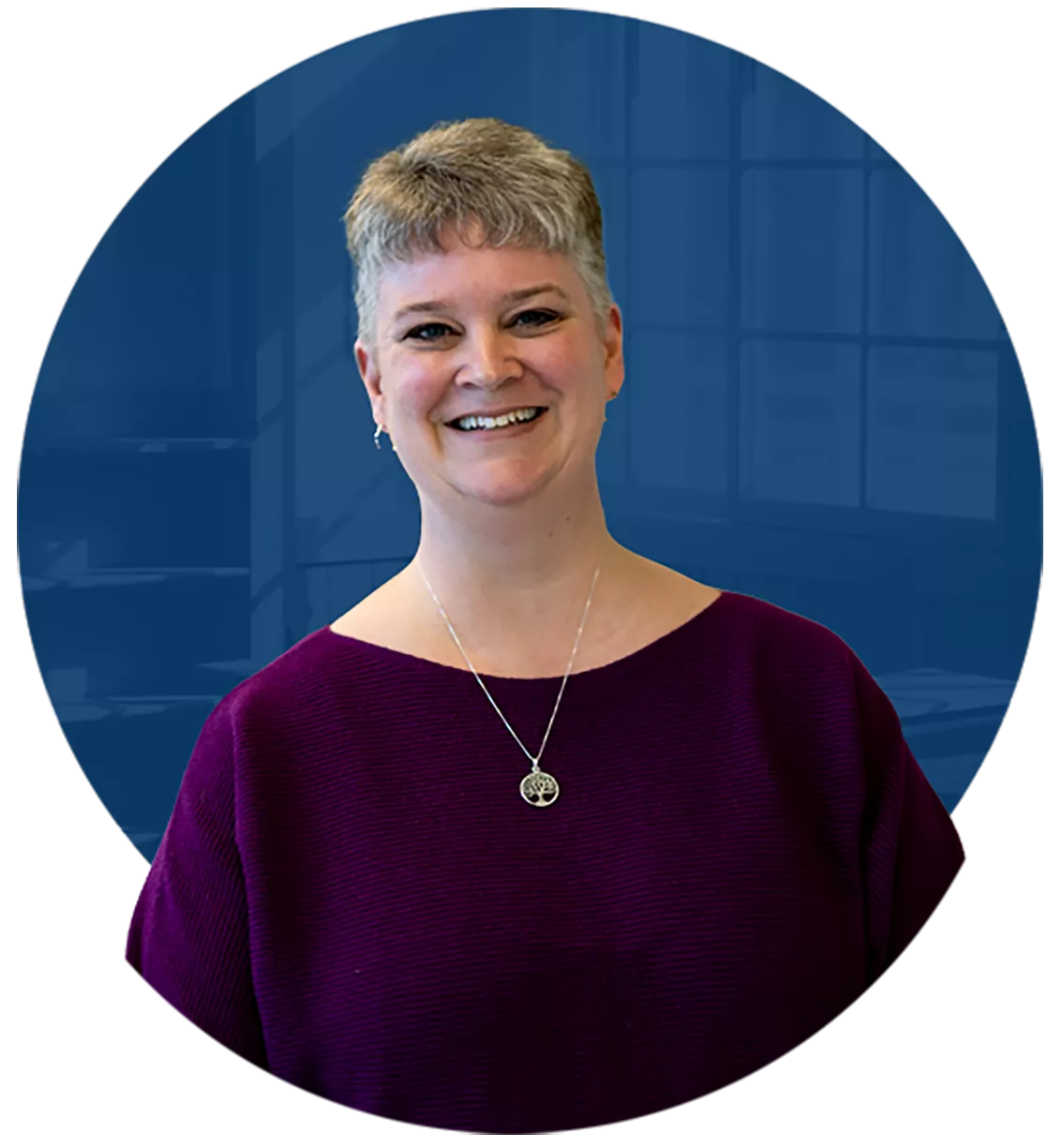 Erin Willoughby, a person with short hair wearing a purple blouse and smiling.
