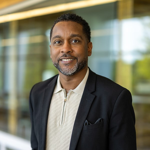 African American male with black suit jacket and cream shirt with collar.