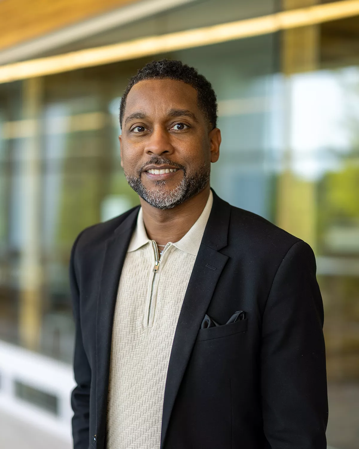 African American male with black suit jacket and cream shirt with collar.