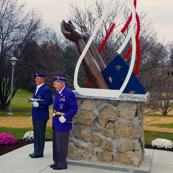 Two military members in front of Fallen Warrior Memorial statue.