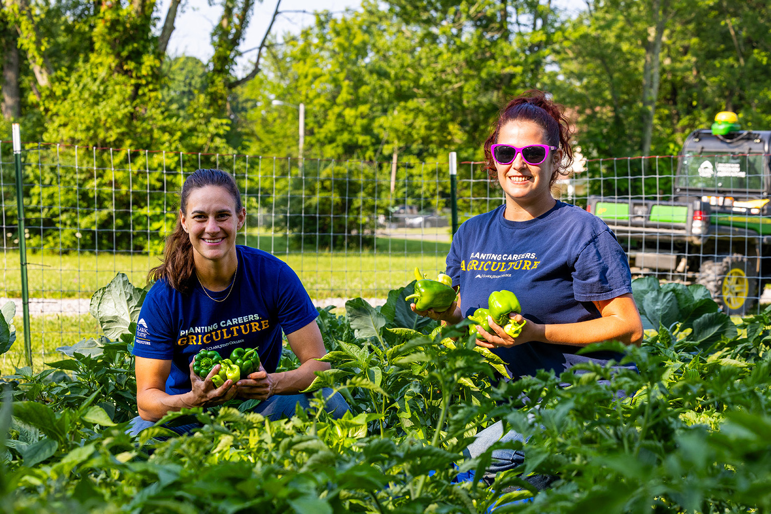 Student wearing a ball cap and plaid shirt using a trowel to put dirt into a plastic pot.