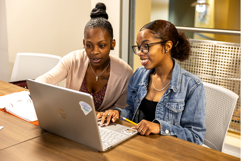Two female students studying at laptop during class.