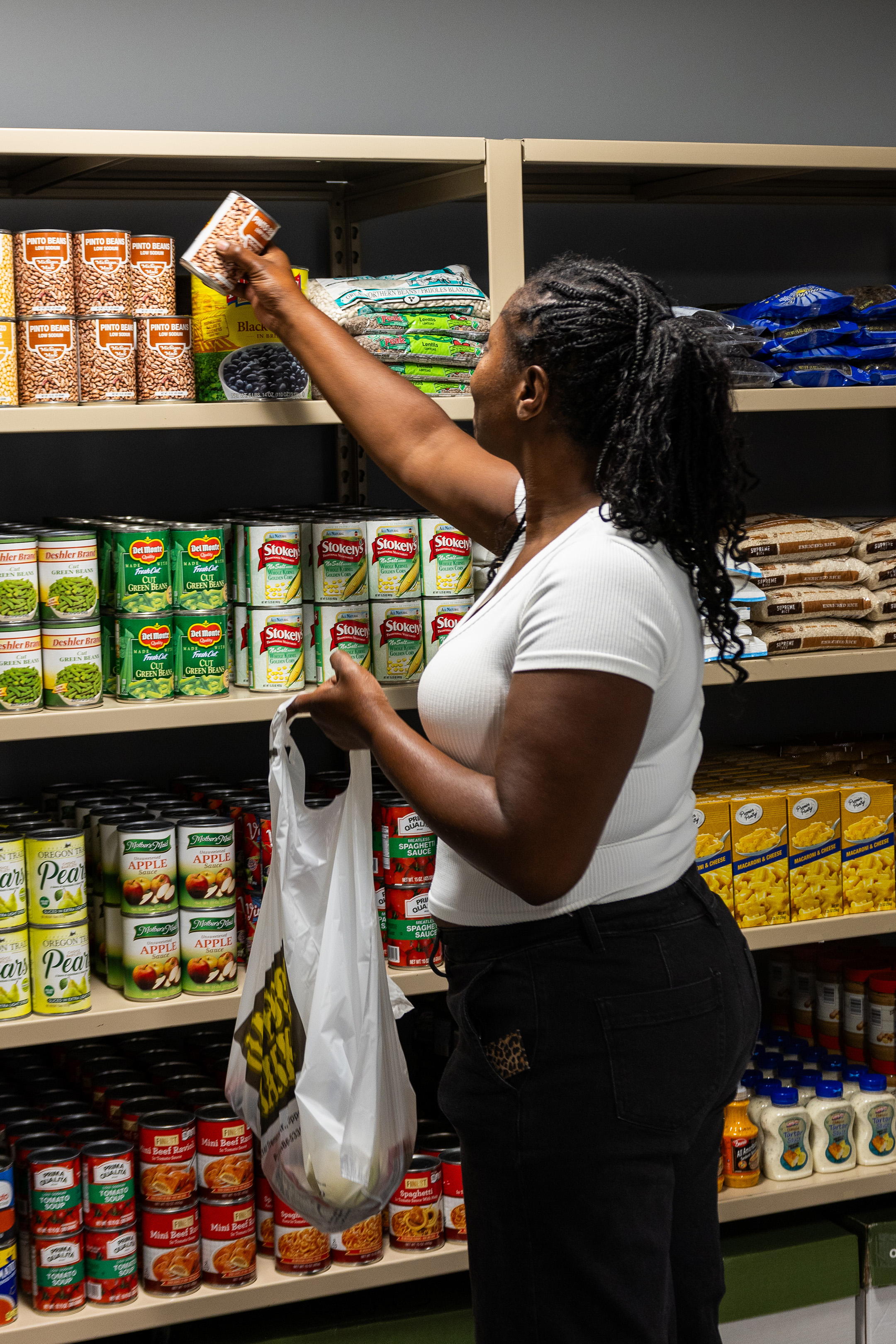 Student filling grocery bag with food from shelves.