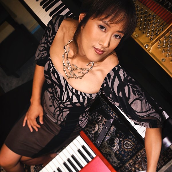 Vienna Teng - woman with dark hair sitting with two keyboards