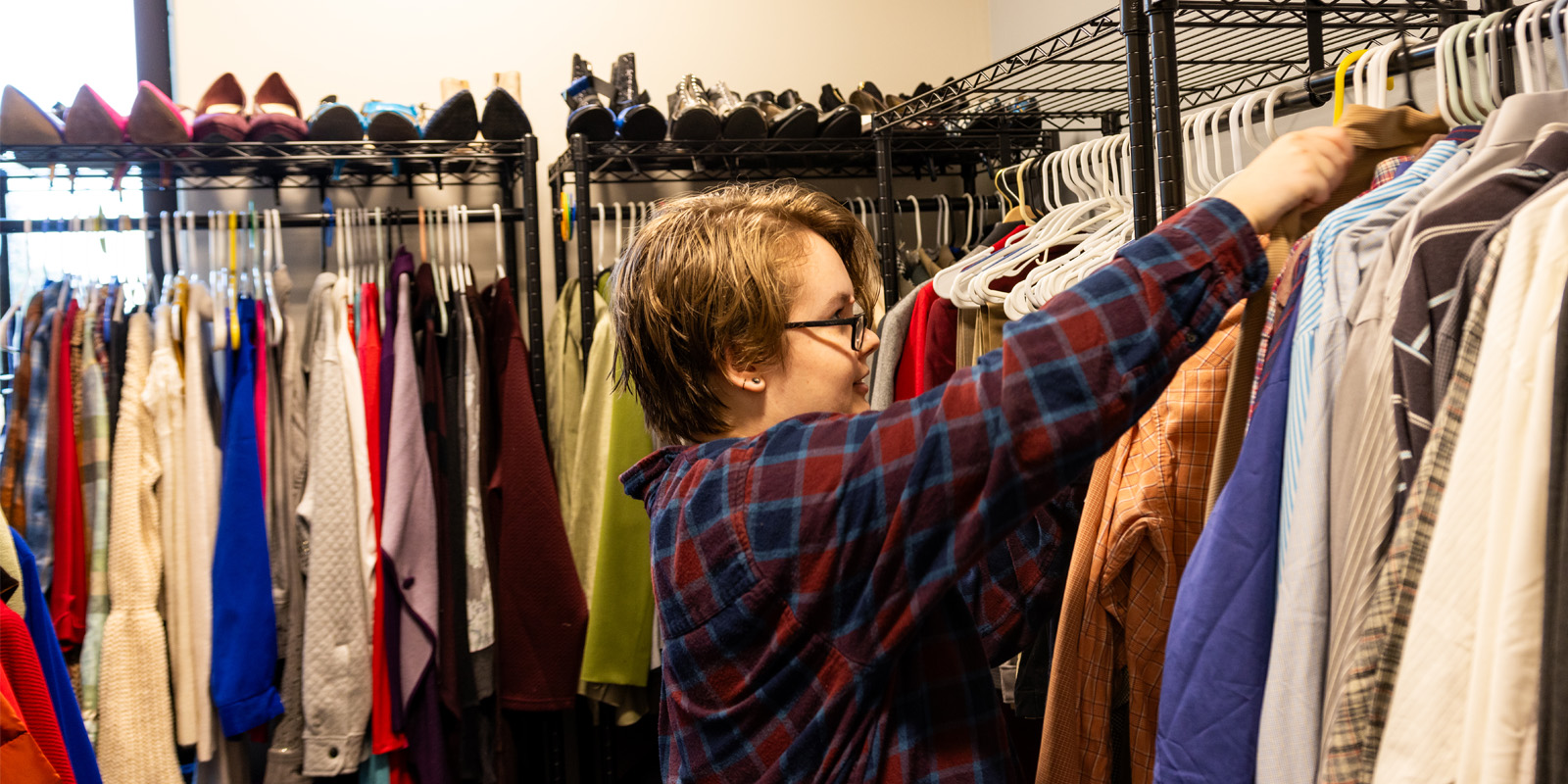 Student hanging clothing in clothing closet