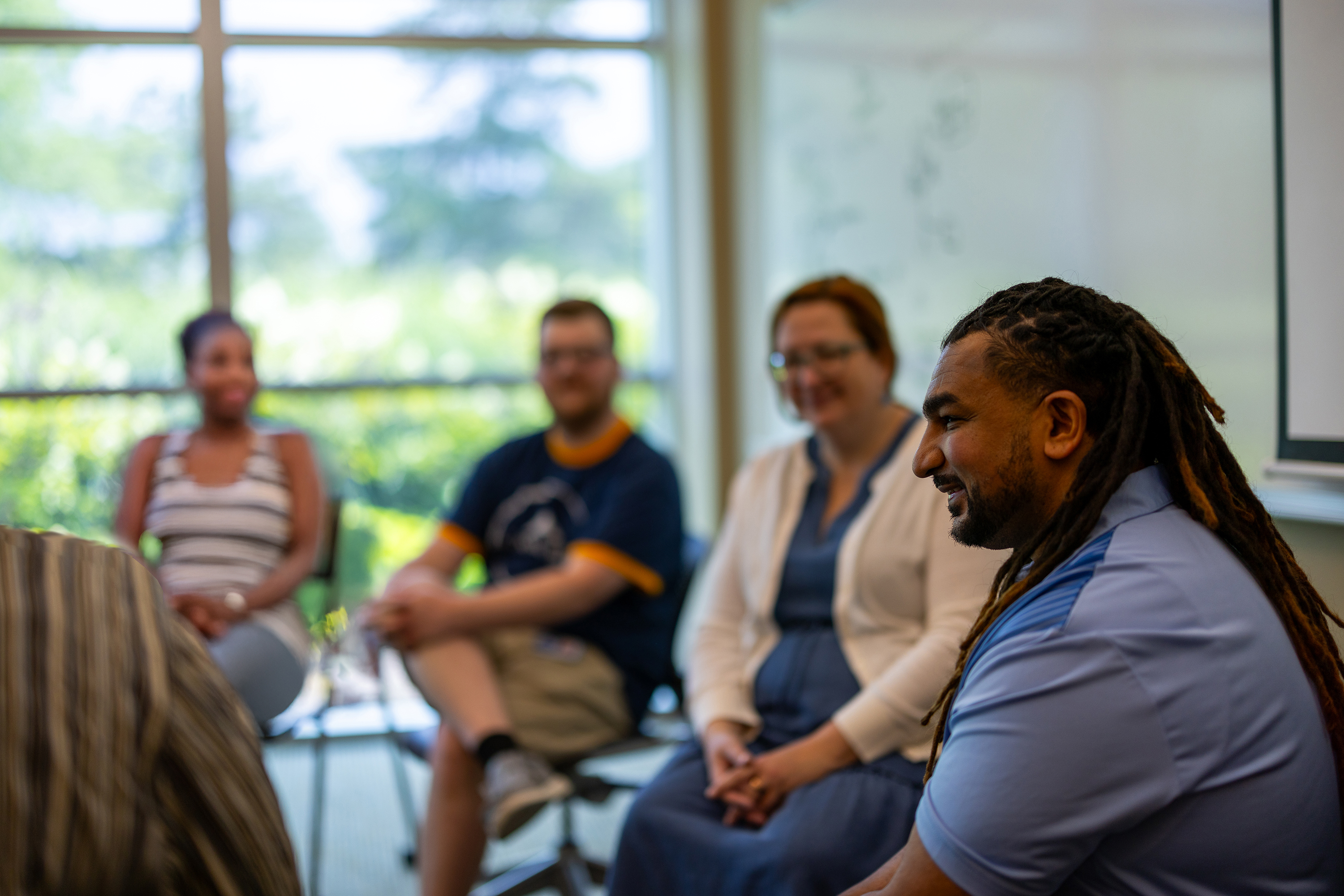 A small group of people sitting in a circle and talking during a discussion or support meeting.