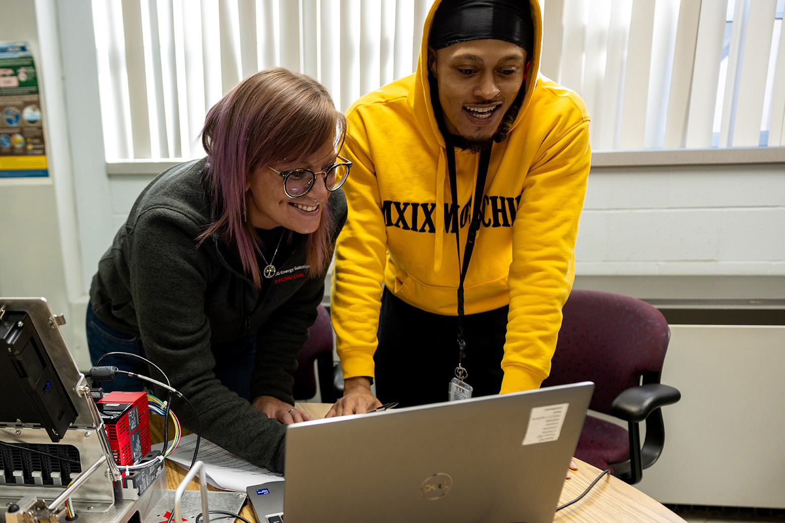 Two students work on laptop.